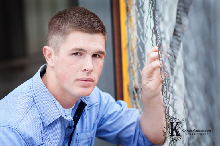 high school senior male in front of chain link