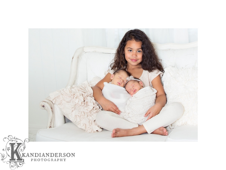 twins snuggling with older sister in studio 